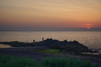 Sunset over Firth of Forth with a rocky island and two anglers in a dark