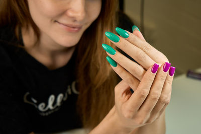Young woman's hands with green and magenta manicure