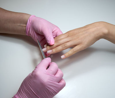 Professional manicurist working with client in beauty salon using nail file