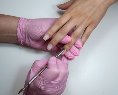 Professional manicurist working with client in beauty salon using cuticle pusher