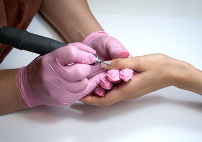 Using an electric nail file, a manicurist buffs off nail polish during a manicure. Close up