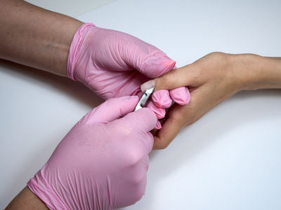 Professional manicurist uses cuticle nippers while working with a client at a beauty salon