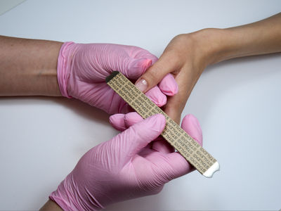 Using a nail file, a manicurist removes nail polish while conducting a manicure.