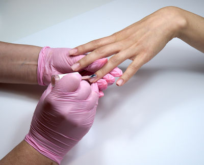 Professional beautician applying nail polish to female nail in a nail salon.