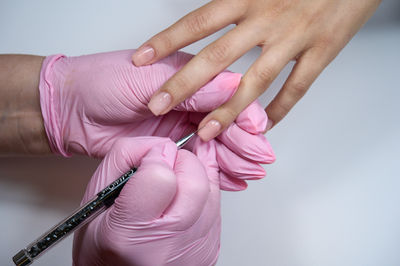 Nail care is provided by a manicurist for a client. in a salon, applying nail polish