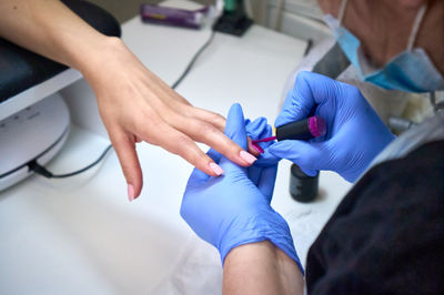 A a manicurist attends to a client's nails. applying nail polish