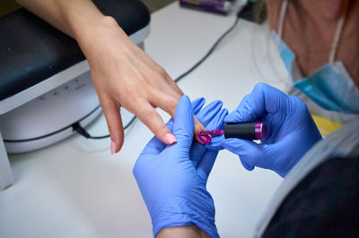 A a manicurist attends to a client's nails. applying nail polish