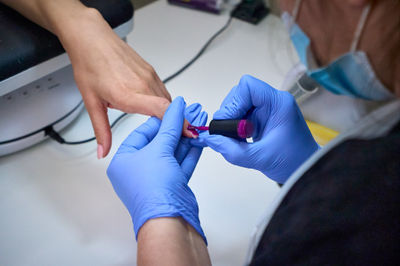 A a manicurist attends to a client's nails. applying nail polish