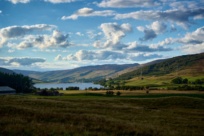 Glen Quaich - Scottish glen with a loch and green fields and forest under colorful sky