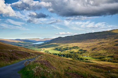 Glen Quaich in Scotland contains a lake, rich farms, and a woods under a clear sky.