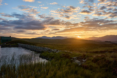 A beautiful Scottish sunset with hills and glens in background and a water reservoir in foreground