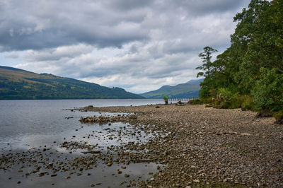 The beaches of Loch Tay, with a gravel beach, a forest, and distant hills