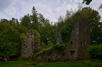 A ruin of Finlarig Castle surrounded by green trees and bushes