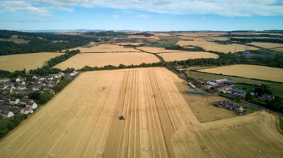 Harvesting - a combine in a barley field under blue sky in a rural aria of Scotland