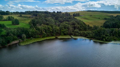 Views of a Scottish lake, green trees and meadows from above.