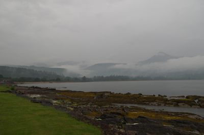 Isle of Arran, Scotland. A serene landscape with water, mountains, and trees. A person stands on a hill overlooking the water. Perfect for relaxation and contemplation.