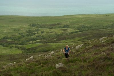 Isle of Arran, Scotland. A young woman fearlessly embraces the challenge of a hill, exploring nature's beauty with vitality and determination.