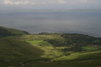 Isle of Arran, Scotland. A serene landscape with green hills, a winding river, and a large body of water. The image captures the beauty of nature under a clear sky.