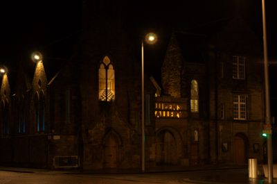 Illuminated building with sign and door. Black line adds depth. Dark arched doorway adds intrigue.