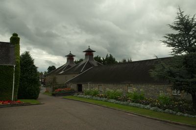 A charming stone building with a sloping roof stands peacefully on a hillside amidst lush greenery. Tranquil and harmonious, it exudes natural beauty.