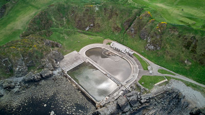 Tarlair Lido - Art Deco outdoor tidal swimming pool, boating pool and paddling pool surrounded by natural landscape. Aerial photo