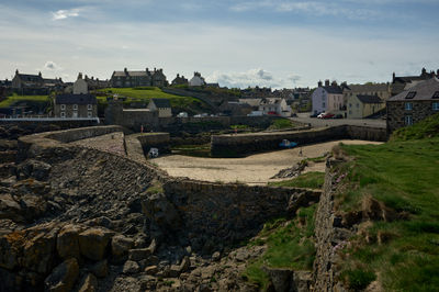 A small coastal town in Scotland with an empty harbour at low tide (no water in sight)