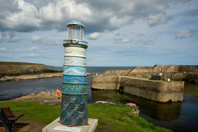 Small colourful lighthouse overlooking a small harbour