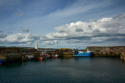 A small harbour with a lighthouse and some boats on a sunny day