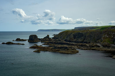 A coastal view - sea, rocks, green shores and a blue sky