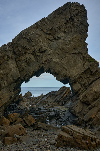 A bizarrely shaped rock with a hole on a seaside