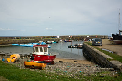 Red fishing boat on a shore and a small harbour behind