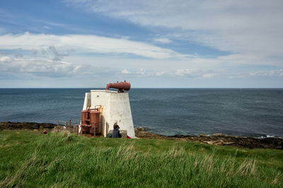 A small white tower with some old equipment (possibly WW2) on a seaside