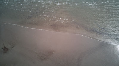 An aerial view of a sandy beach with waves.