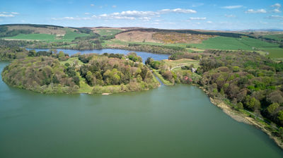 An aerial photograph of a lake with a green island taken on a beautiful day.