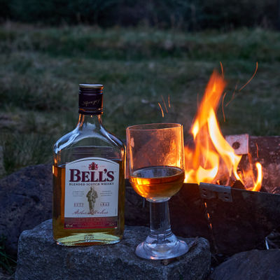 Whisky in a bottle and a glass near a campfire