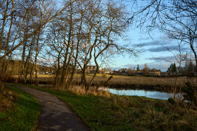 River Teith, Callander, Scotland. A serene path by a calm river, bathed in sunlight, invites exploration.