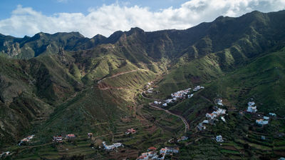 An aerial view of a village on slopes of green mountains on a sunny day, Tenerife