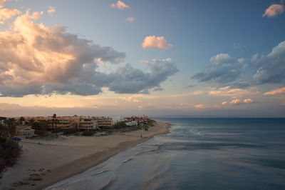 a cloudy sky with a beach and buildings in the foreground of a photo taken from a high point