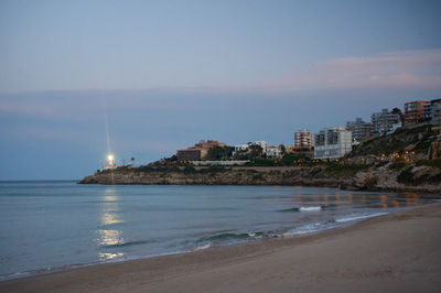 Cullera, Valencia, Spain - 03.13.2023 a beach with buildings and a lighthouse at dusk