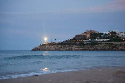 a lighthouse on a beach at dusk