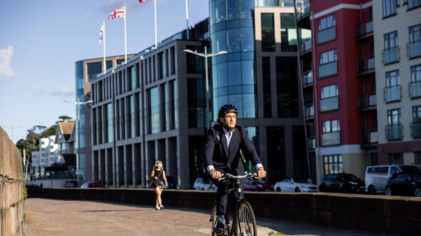 Businessman commuting by bike along a city waterfront.