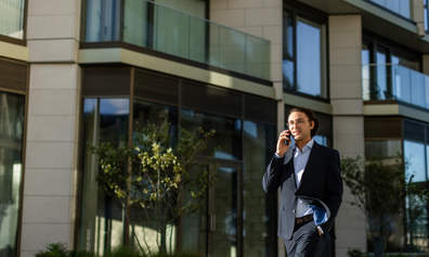 Man walking while on a phone call outside an office building