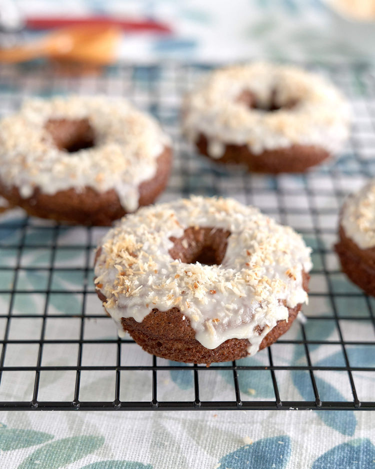 Gluten-free donut with coconut icing on a cooling rack.