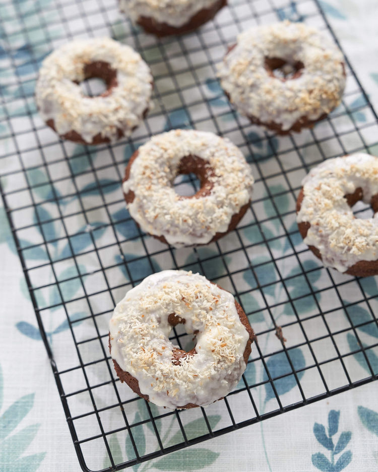 Gluten-free donut with coconut icing on a cooling rack.