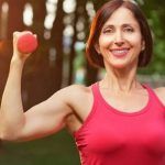 Middle aged woman lifts dumbbells outdoors