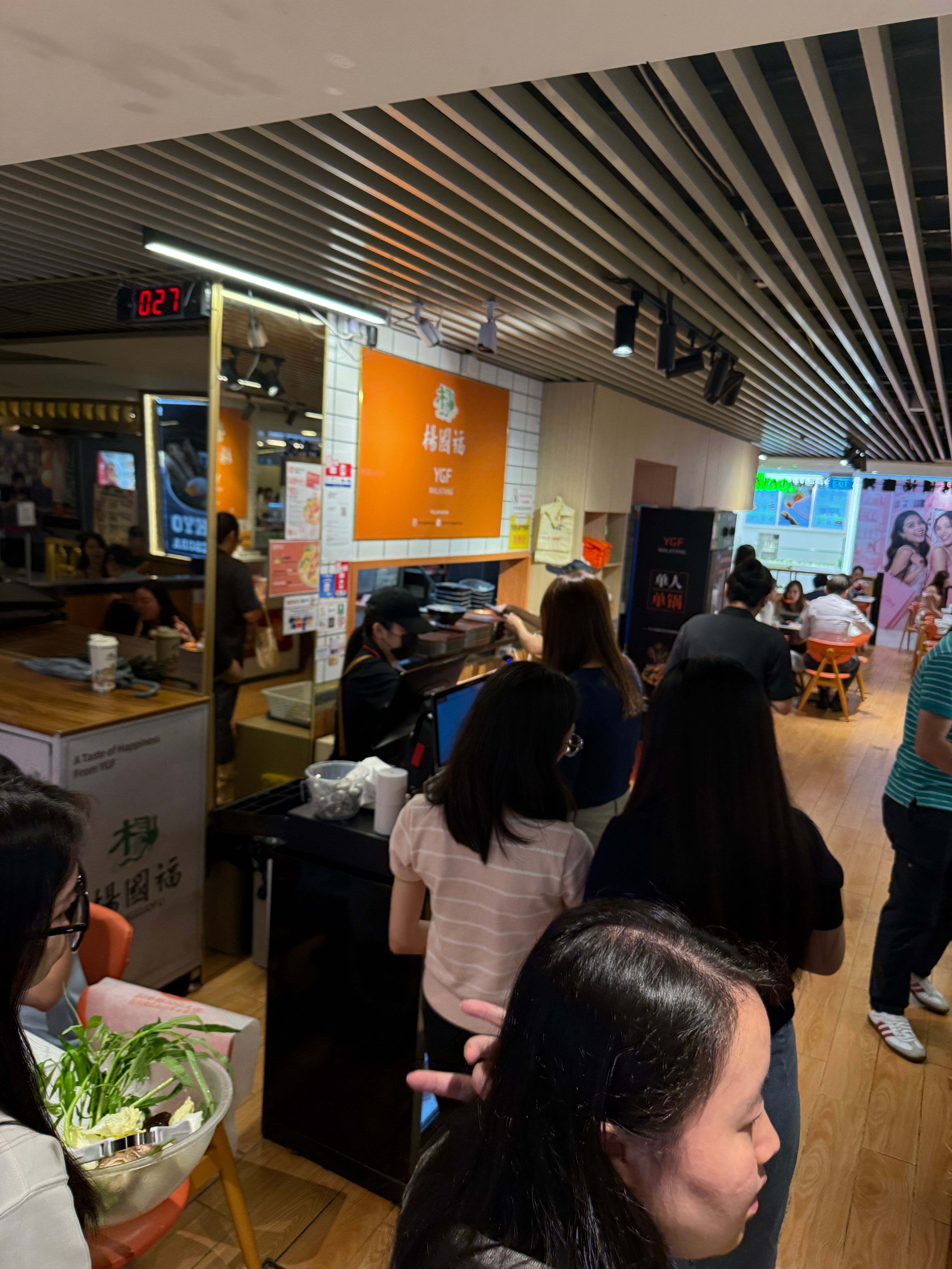 Queue at Yang Guo Fu Mala Tang Plaza Singapura YGF Malatang with orange brand signage and ingredient bar