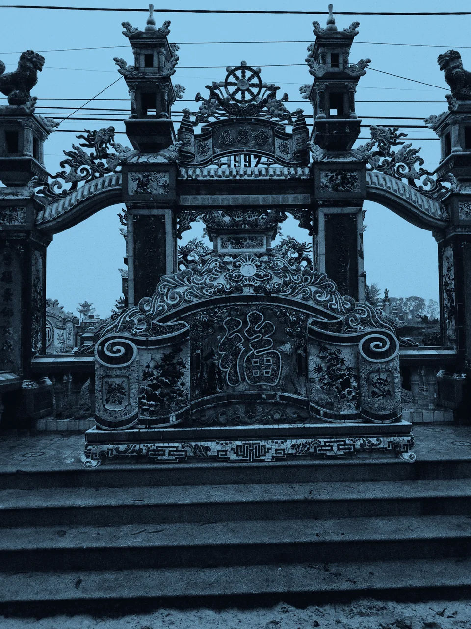 An ornate gate and decorative screen above stone steps.
