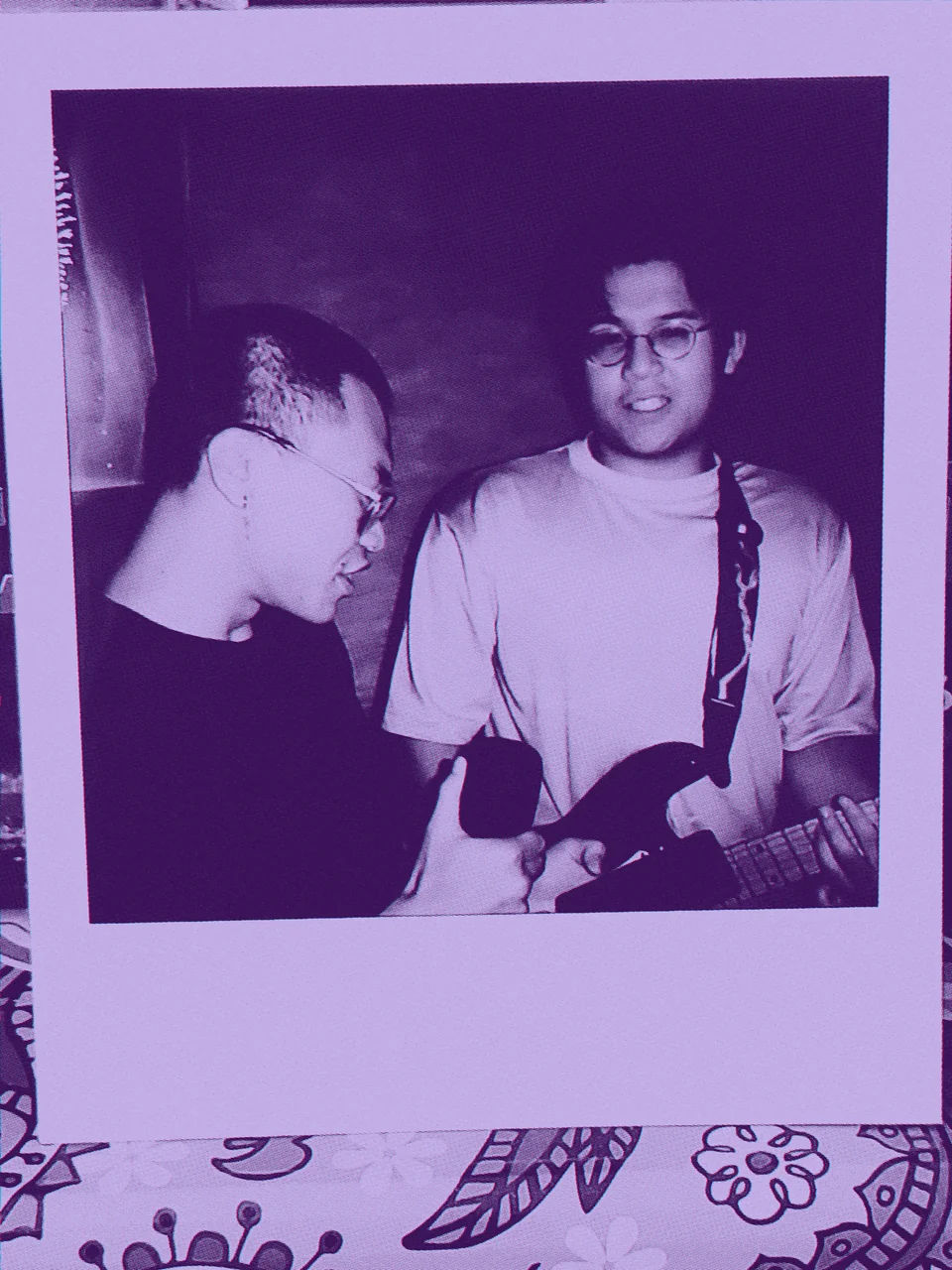 An instant photo of two people with a guitar.