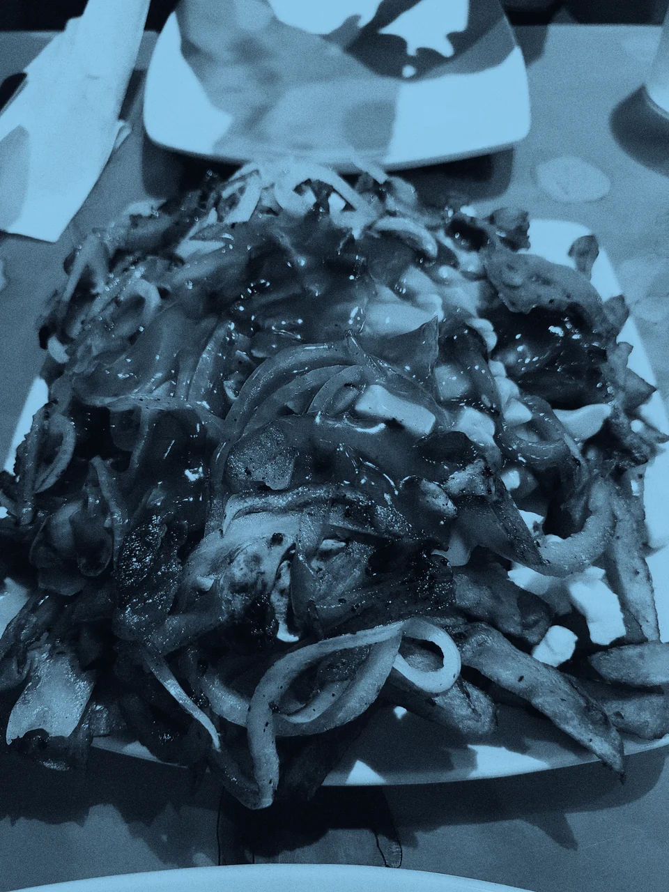A plate of poutine topped with peppers and onions.
