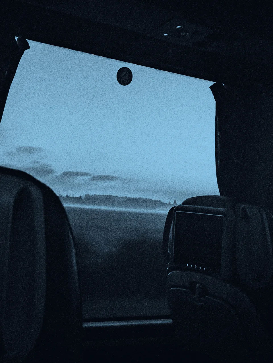 A misty landscape seen through a bus window.